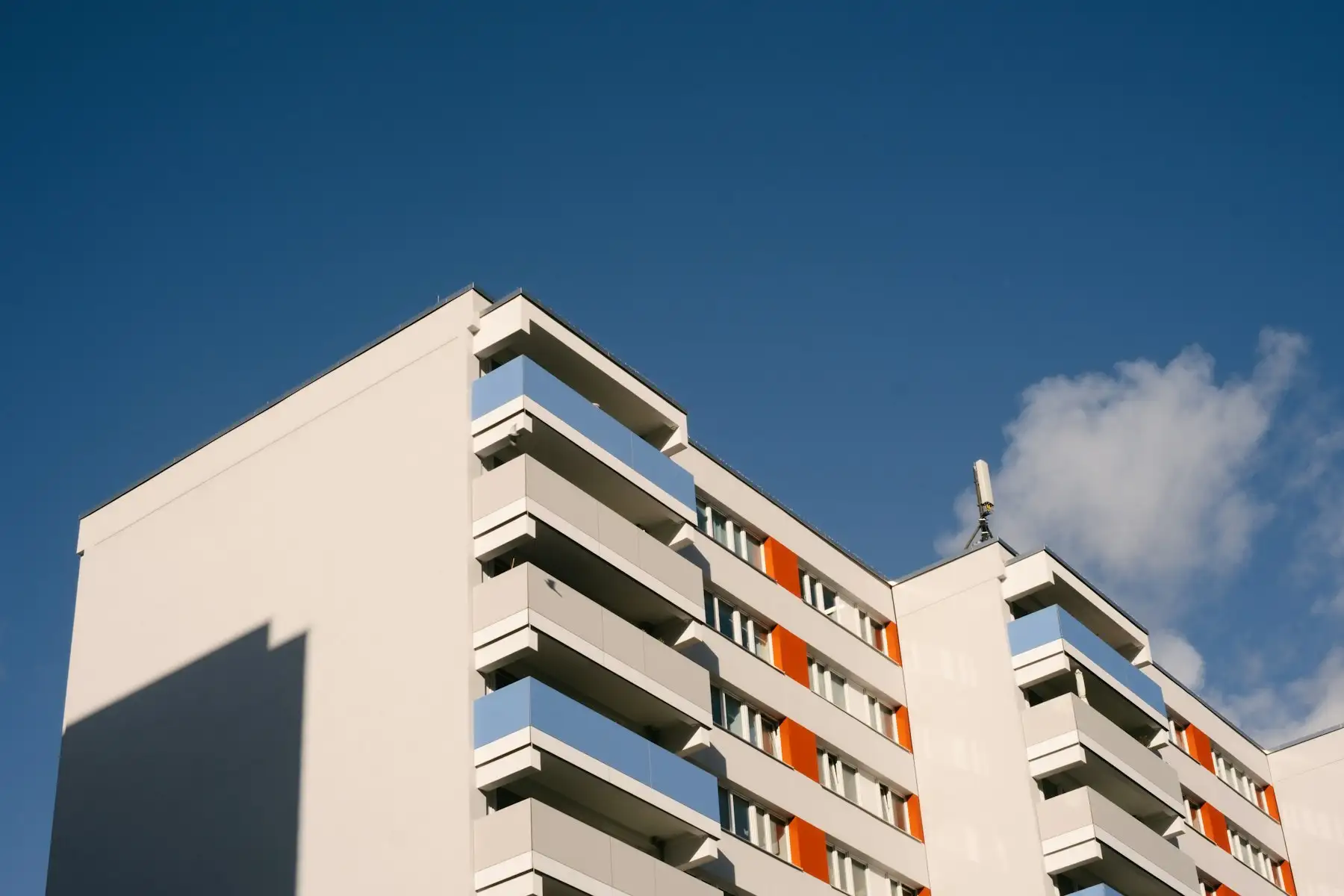 White apartment building with balconies against a blue sky