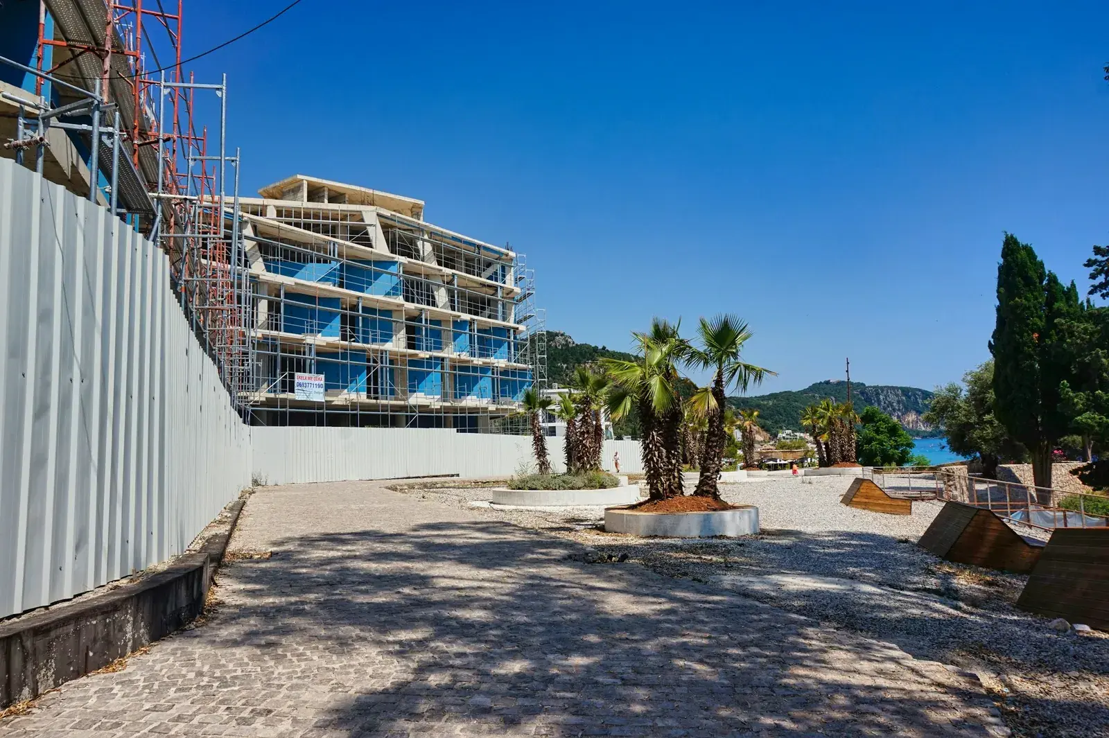 A residential building under construction with scaffolding and hoarding in Dhërmi, Albania