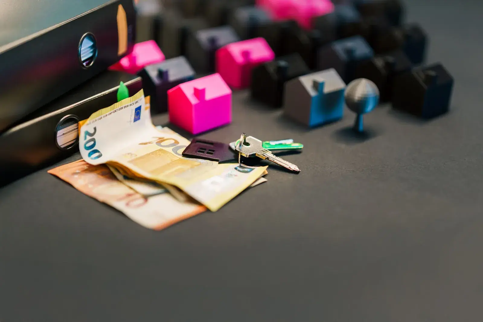 Euro banknotes, keys and miniature houses on a table