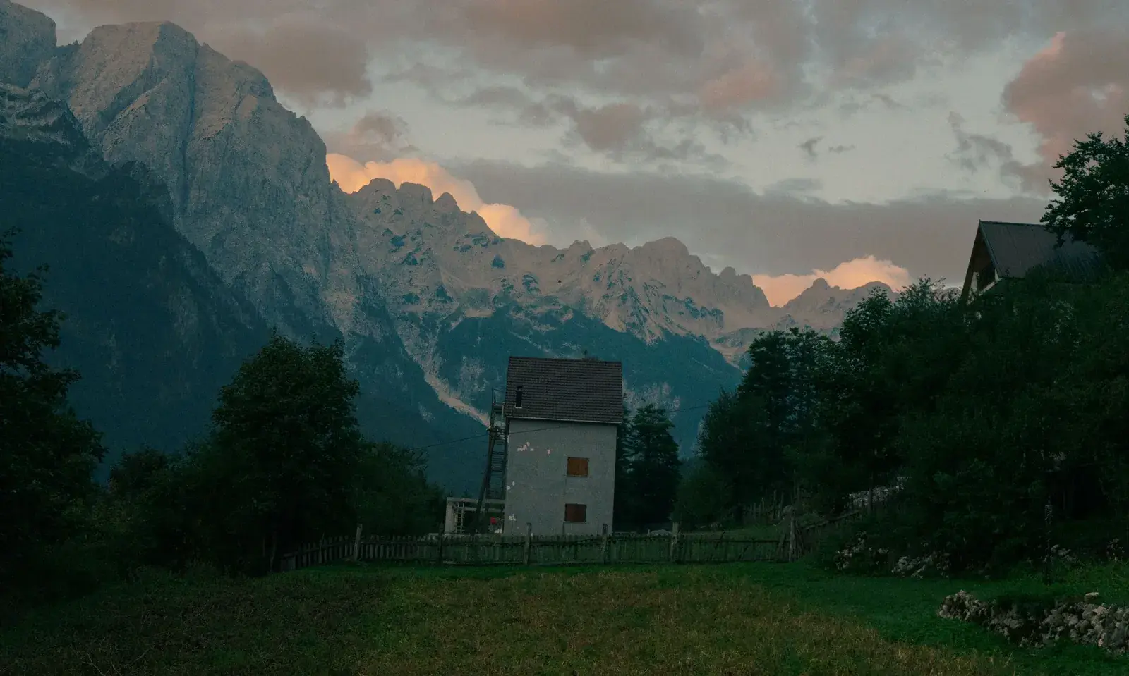 A lone house in the Valbona valley beneath the peaks of the Albanian Alps at dusk