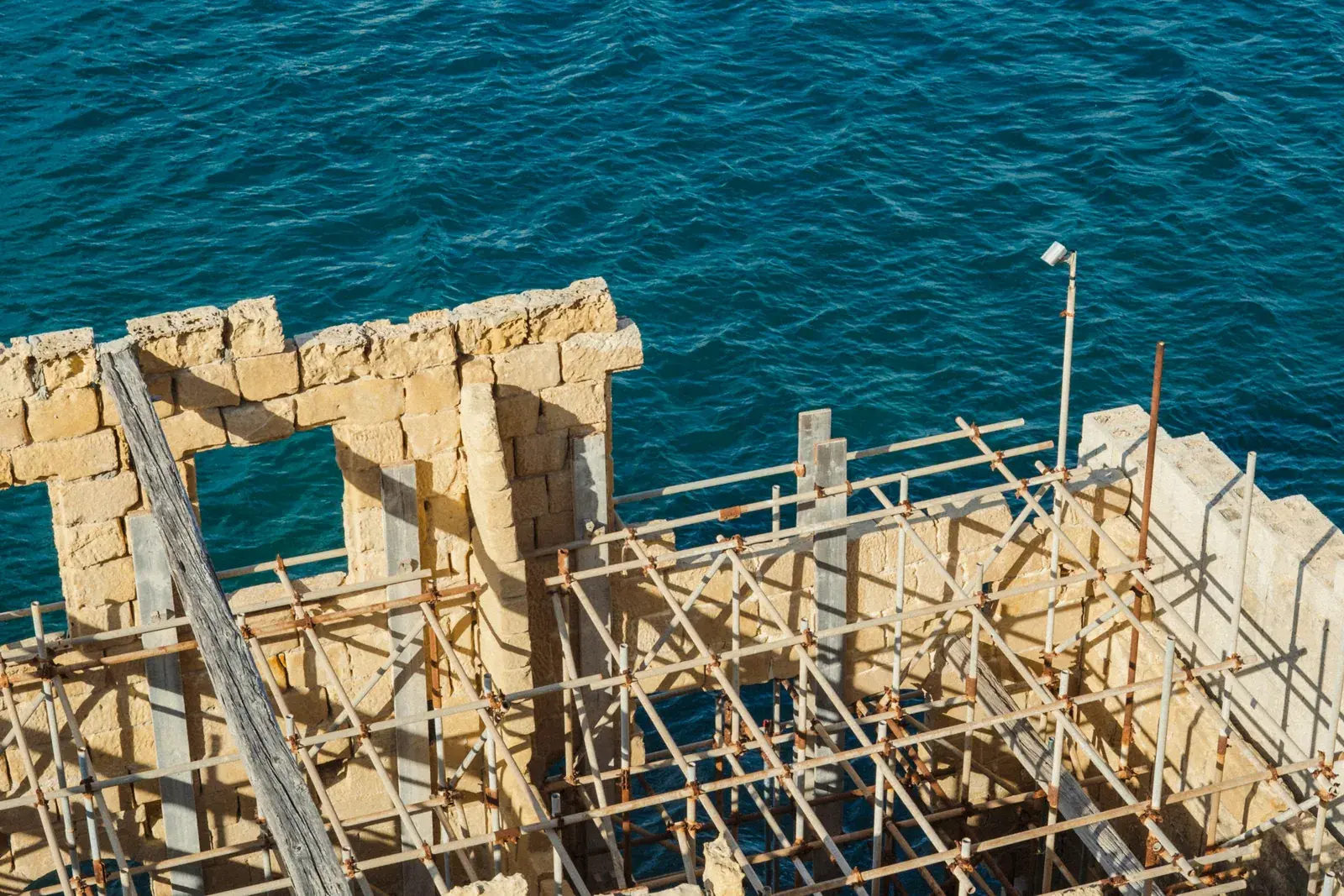 New building with scaffolding right by the sea, seen from above