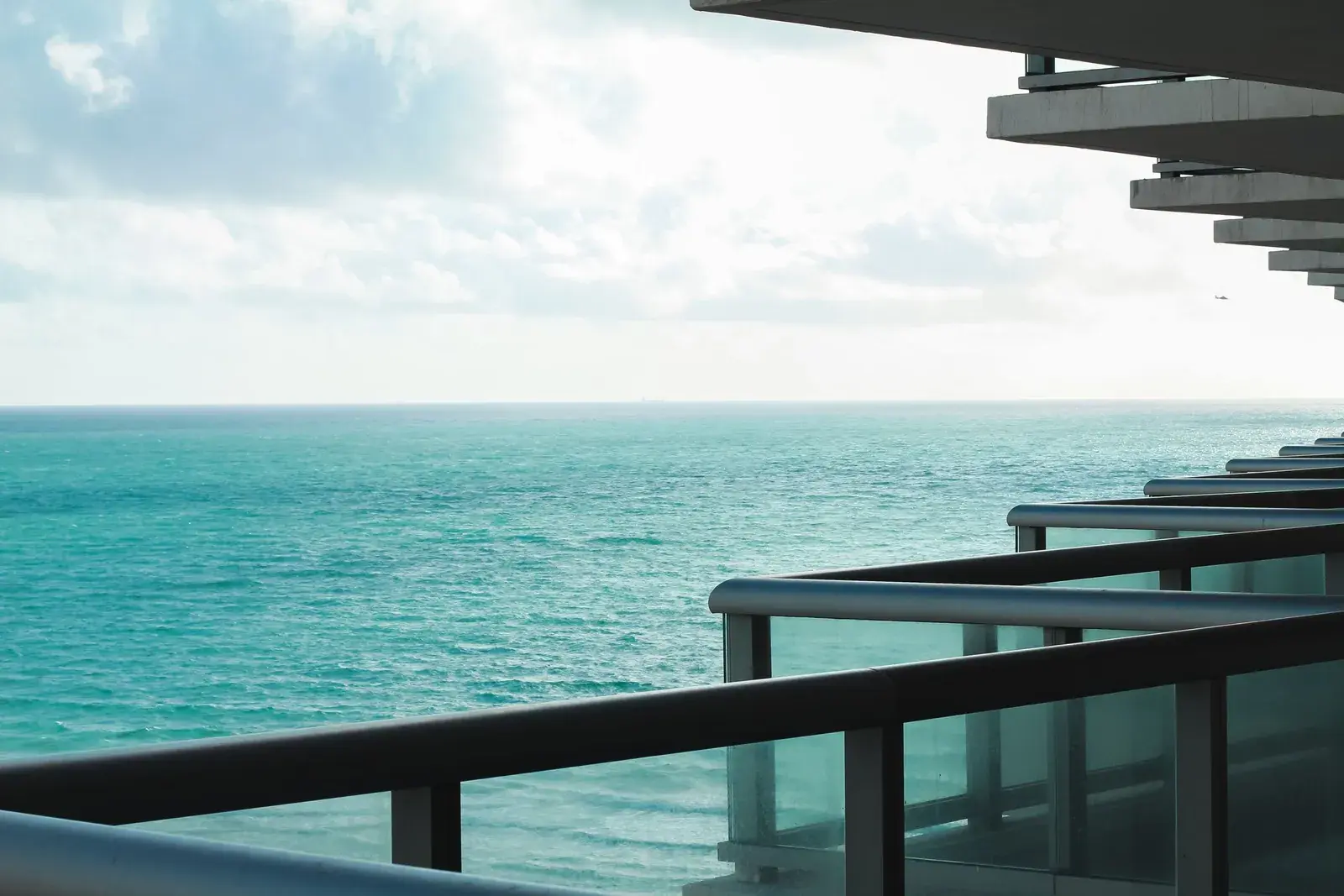 Wohnungsbalkon mit Glasgeländer und Blick aufs Meer