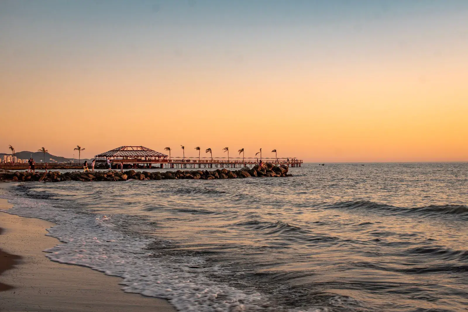Sunset on Golem beach, with gentle waves and a pier