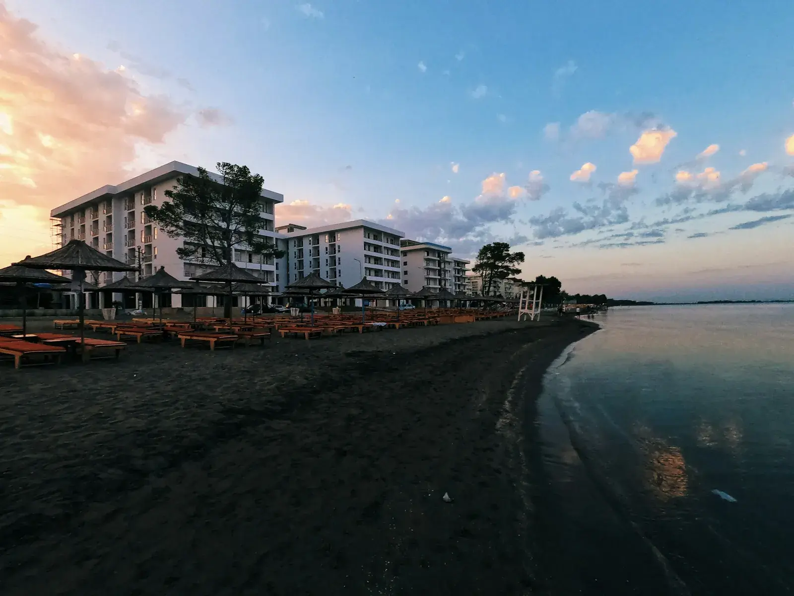 Plazhi i Shëngjinit i qetë në agim, me pallate dhe çadra të mbyllura