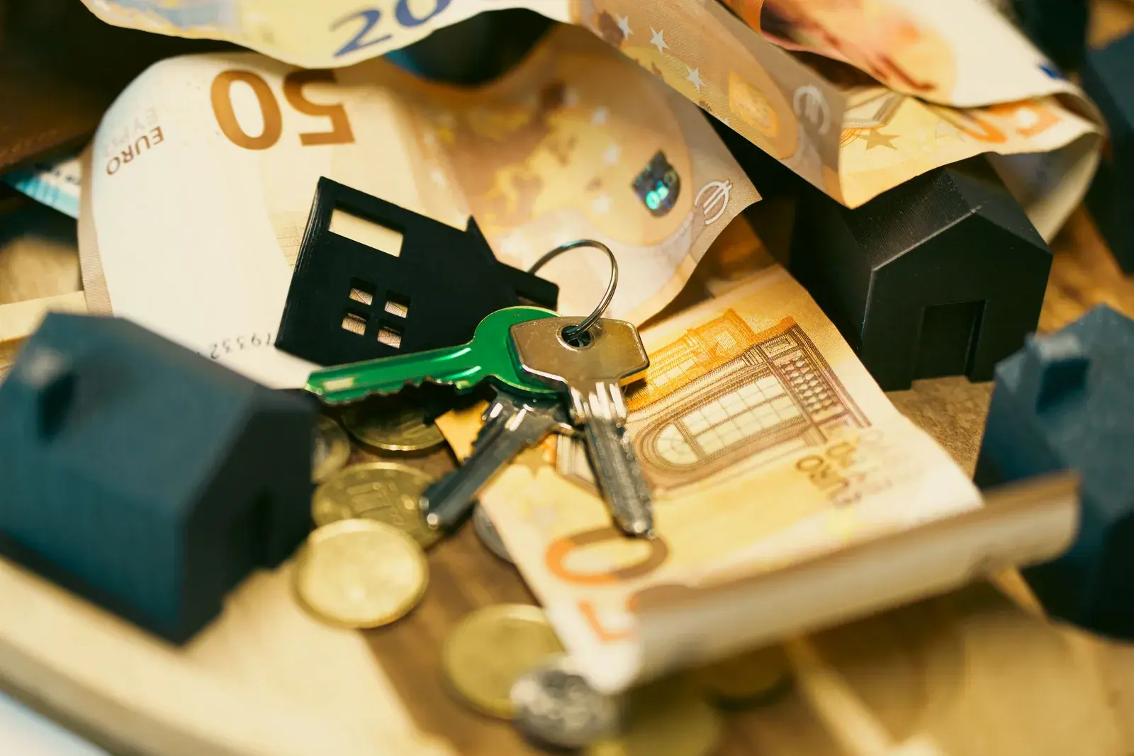 Çelësa shtëpie, modele të vogla shtëpish dhe kartëmonedha euro mbi tavolinë