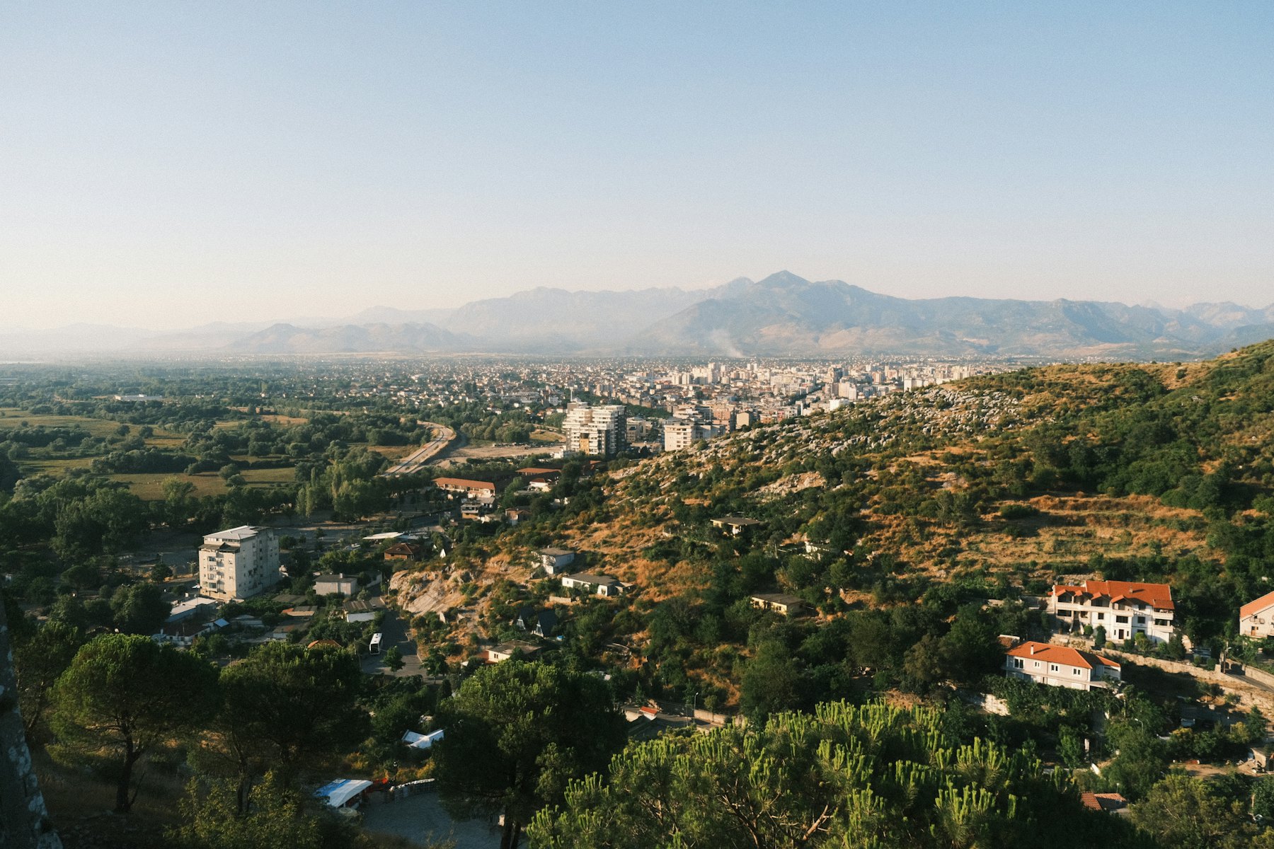 A sprawling cityscape nestled among rolling hills
