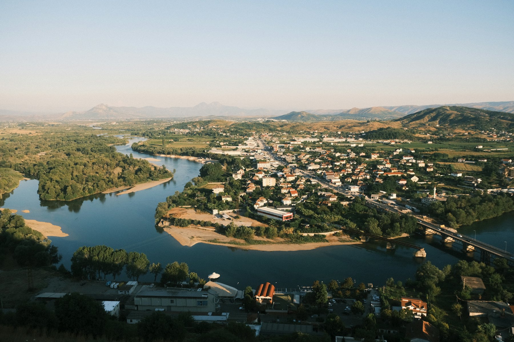 River bends around a town nestled in rolling hills