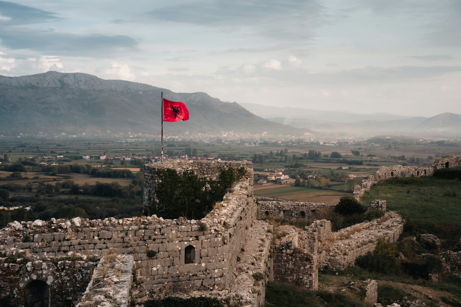 The red flag of Albania flying over the stone ruins of Rozafa Castle